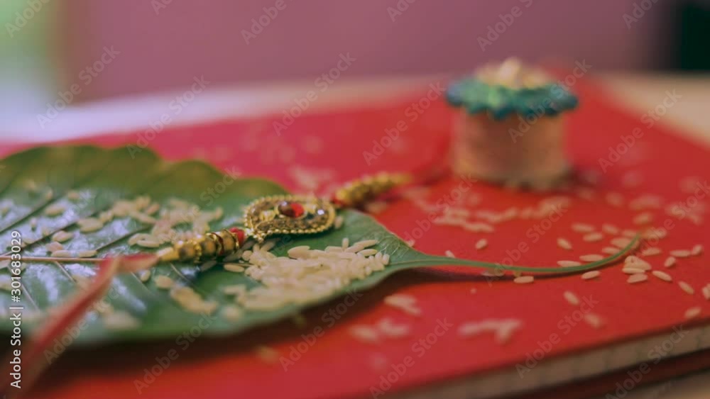 Raksha bandhan rakhi with rice , green leaf on red background Raksha bandhan rakhi with rice , green leaf on red background