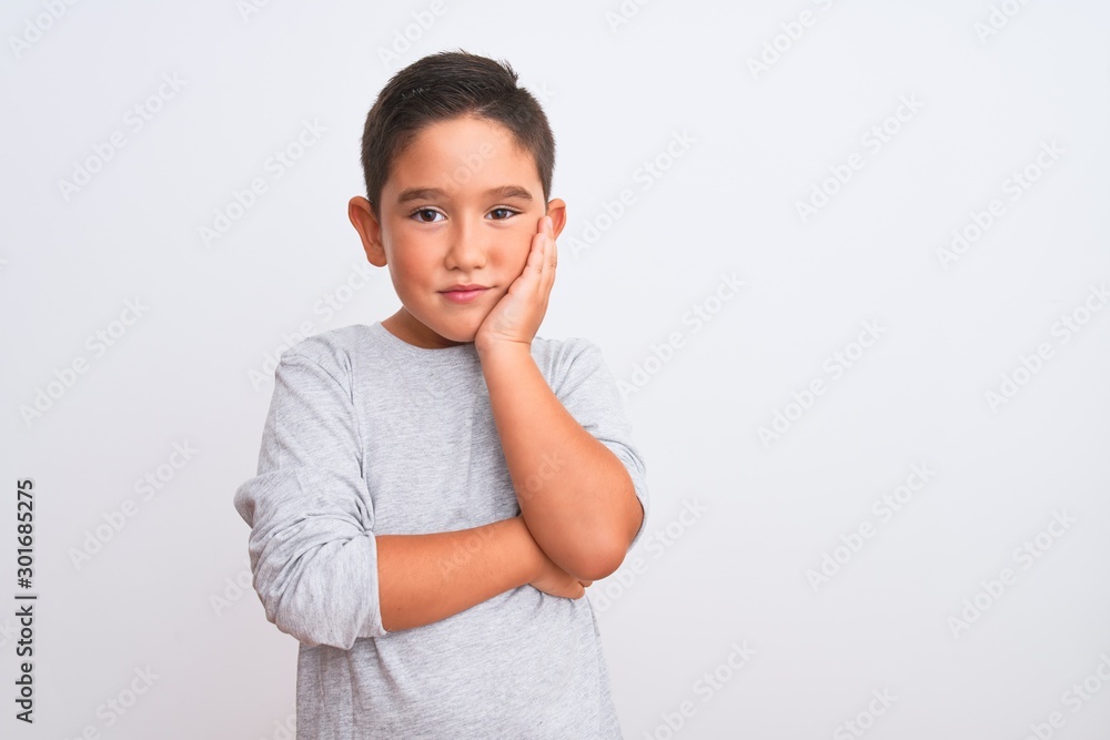 Beautiful kid boy wearing grey casual t-shirt standing over isolated white background thinking looking tired and bored with depression problems with crossed arms. Beautiful kid boy wearing grey casual t-shirt standing over isolated white background thinking looking tired and bored with depression problems with crossed arms.