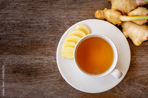  white cup of hot ginger tea isolated on wood table background .