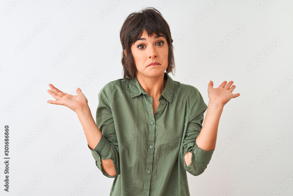Young beautiful woman wearing green casual shirt standing over isolated white background clueless and confused expression with arms and hands raised. Doubt concept. Young beautiful woman wearing green casual shirt standing over isolated white background clueless and confused expression with arms and hands raised. Doubt concept.