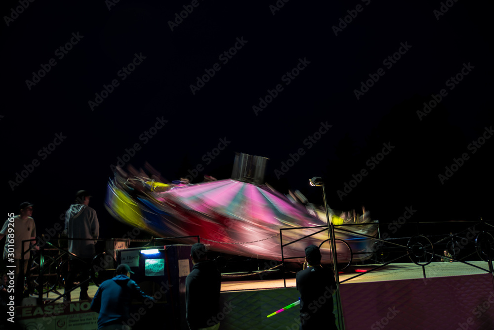 Amusement park ride fast spinning carousel roundabout with motion blur. Fun fair carnival rides at fairground. Family vacation, leisure and recreation concept Amusement park ride fast spinning carousel roundabout with motion blur. Fun fair carnival rides at fairground. Family vacation, leisure and recreation concept