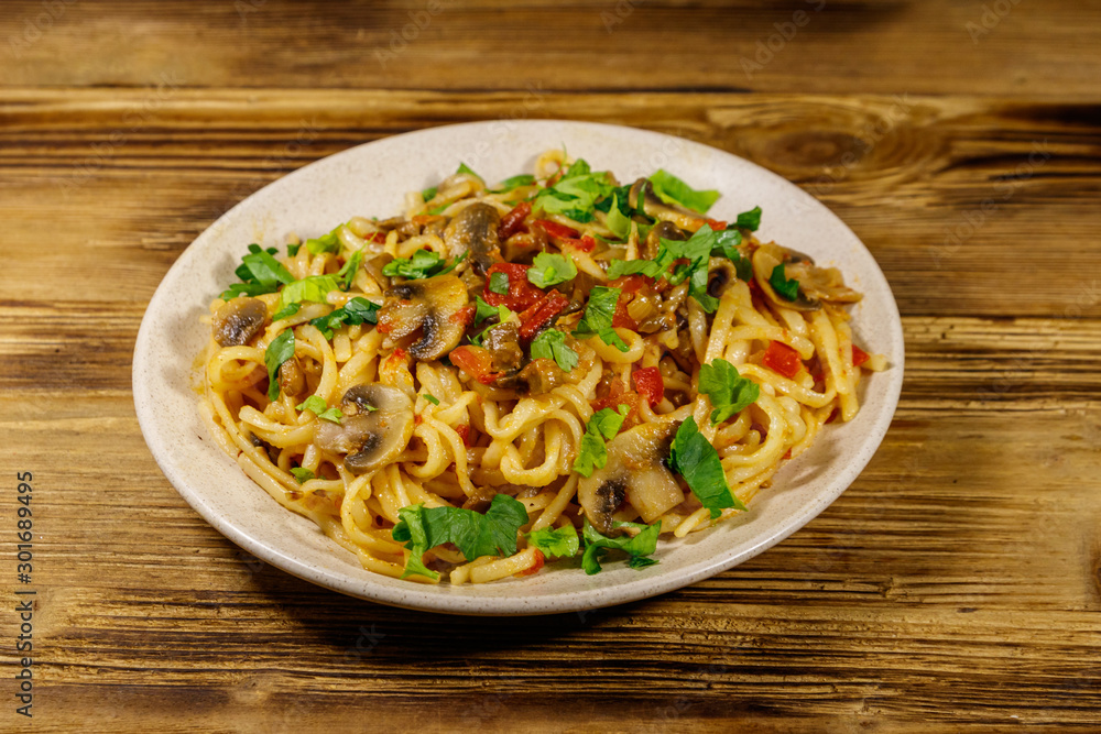 Pasta with mushrooms and tomato sauce on wooden table