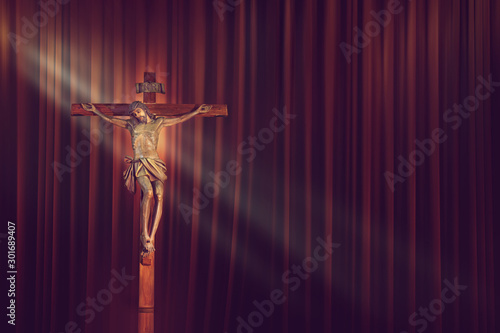 crucifix, jesus on the cross in church with ray of light on red curtain background