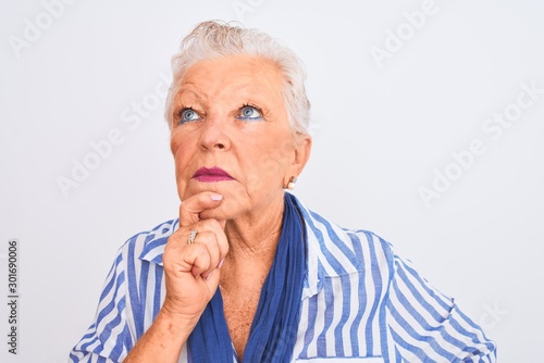 Senior grey-haired woman wearing blue striped shirt standing over isolated white background serious face thinking about question, very confused idea