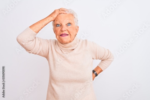 Senior grey-haired woman wearing turtleneck sweater standing over isolated white background smiling confident touching hair with hand up gesture, posing attractive and fashionable