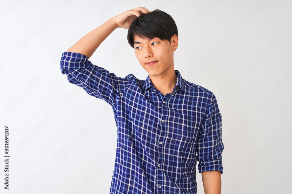 Young chinese man wearing casual blue shirt standing over isolated white background confuse and wonder about question. Uncertain with doubt, thinking with hand on head. Pensive concept. Young chinese man wearing casual blue shirt standing over isolated white background confuse and wonder about question. Uncertain with doubt, thinking with hand on head. Pensive concept.