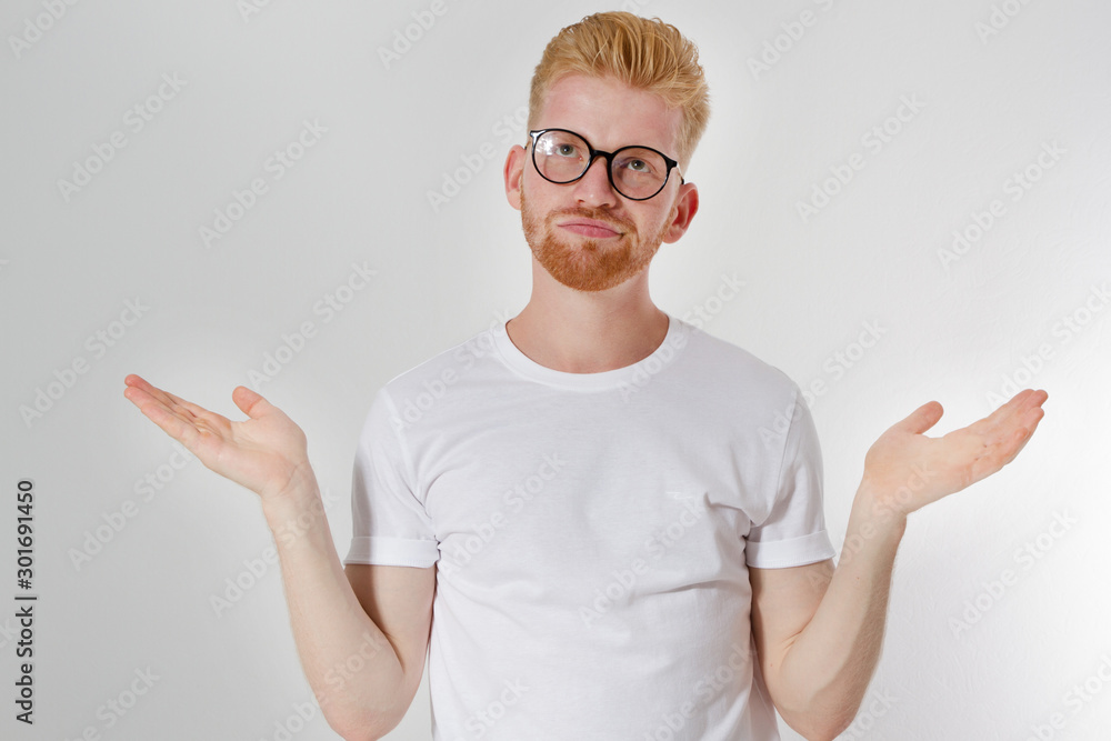 I do not know what to choose concept, European- looking red hair man of 30 years with glasses and white t-shirt, does not know