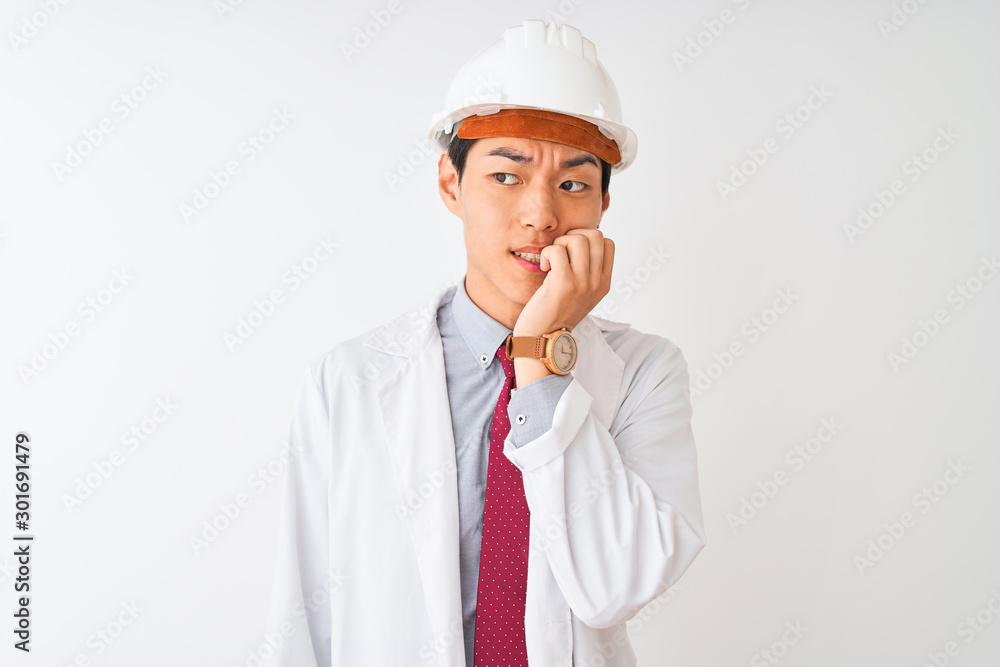 Chinese architect man wearing coat and helmet standing over isolated white background looking stressed and nervous with hands on mouth biting nails. Anxiety problem. Chinese architect man wearing coat and helmet standing over isolated white background looking stressed and nervous with hands on mouth biting nails. Anxiety problem.