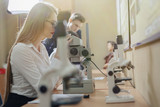 two girls and a boy work with microscopes