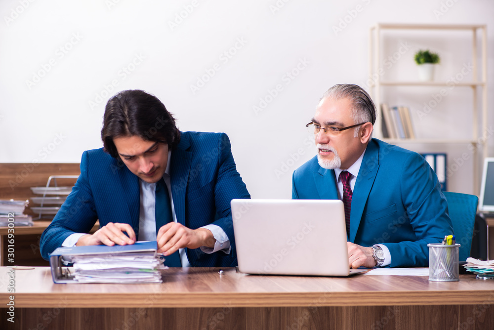 Young and old employees working together in the office Young and old employees working together in the office