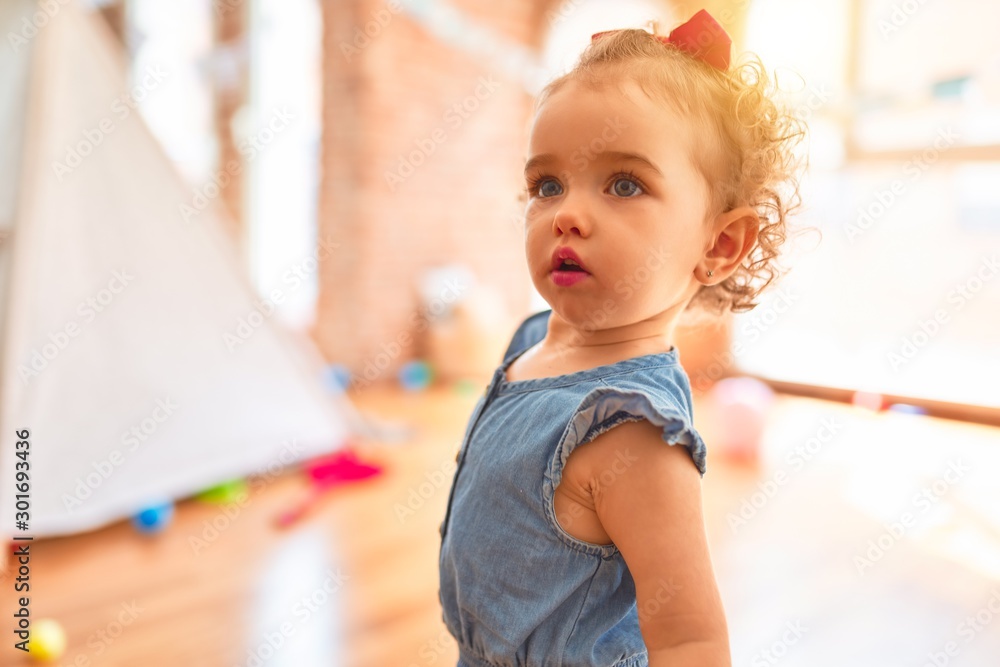 Beautiful caucasian infant playing with toys at colorful playroom. Happy and playful at kindergarten. Beautiful caucasian infant playing with toys at colorful playroom. Happy and playful at kindergarten.