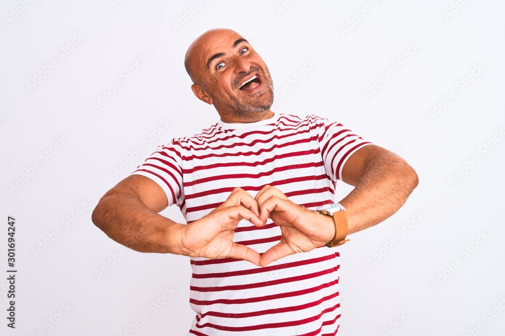 Middle age handsome man wearing striped t-shirt standing over isolated white background smiling in love showing heart symbol and shape with hands. Romantic concept. Middle age handsome man wearing striped t-shirt standing over isolated white background smiling in love showing heart symbol and shape with hands. Romantic concept.