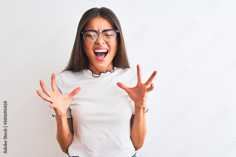 Young beautiful woman wearing casual t-shirt and glasses over isolated white background celebrating mad and crazy for success with arms raised and closed eyes screaming excited. Winner concept - obrazy, fototapety, plakaty 