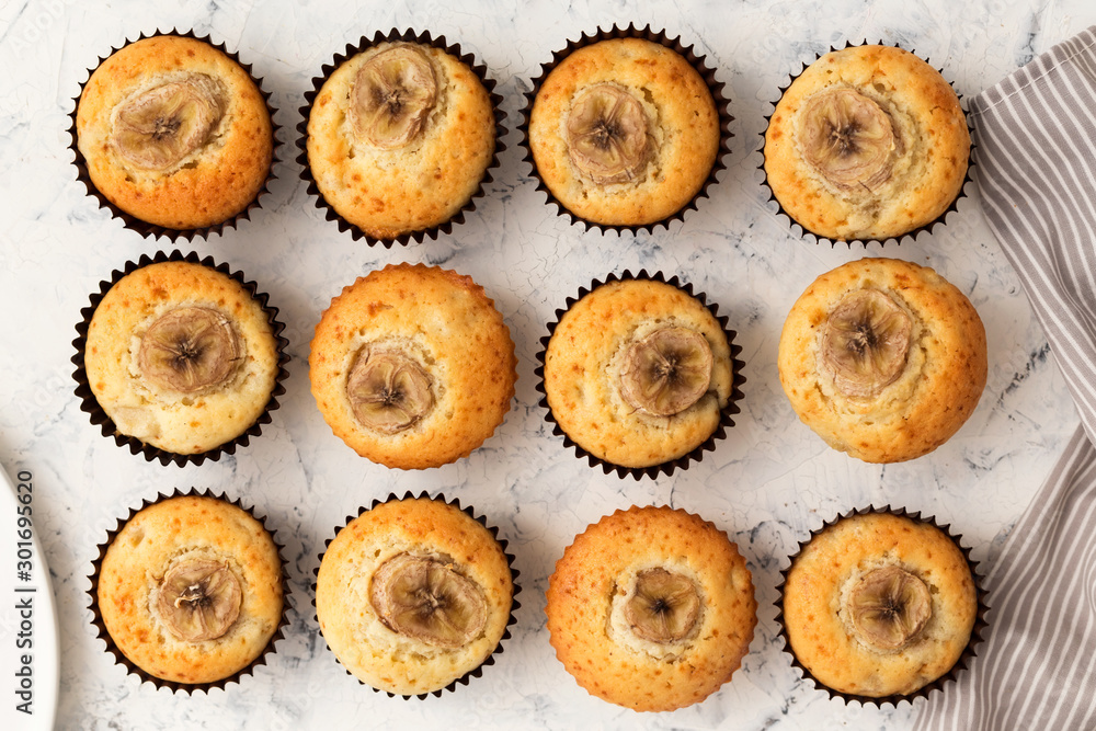 Banana muffins on a white table. Sweet cupcakes with slice of fruit. Flat lay, top view