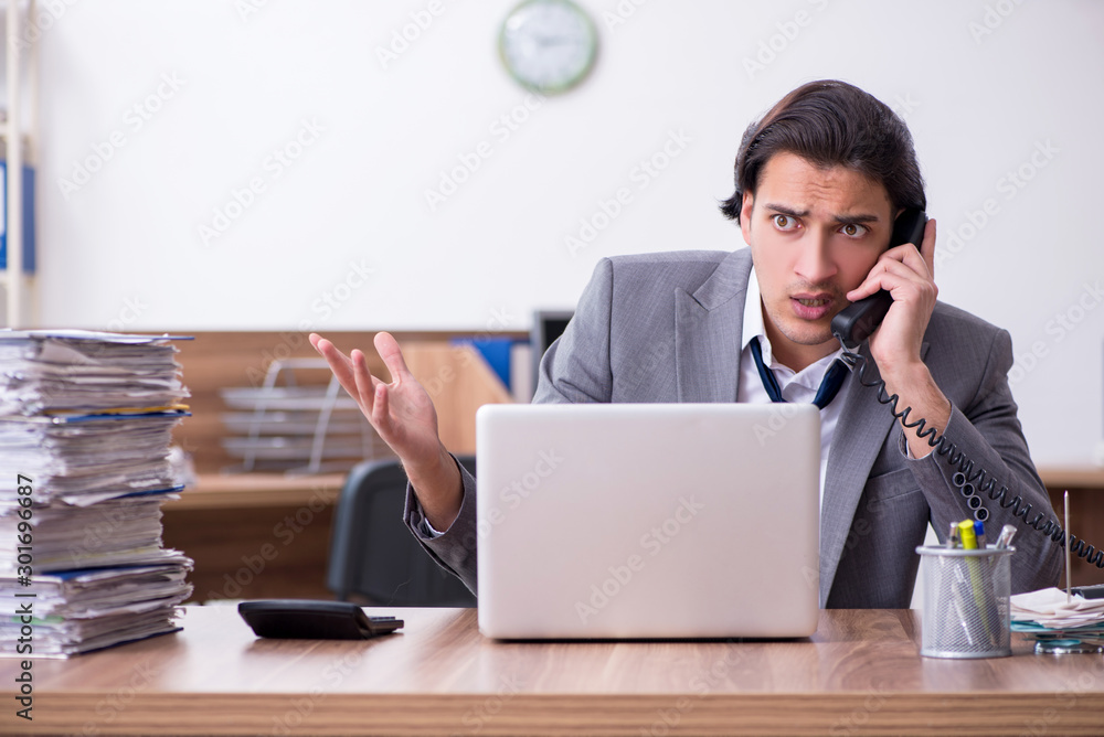 Young male employee unhappy with excessive work Young male employee unhappy with excessive work