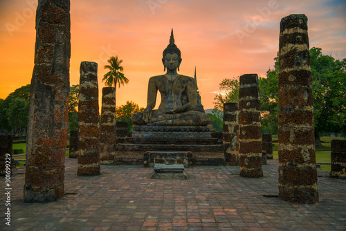 An ancient sculpture of a sitting Buddha against the sunset on the ruins of the Buddhist temple Wat Chana Songkram. Sukhothai Historical Park, Thailand