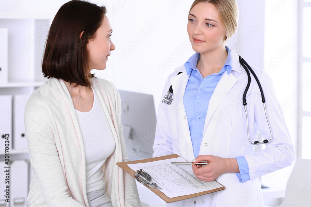 Young woman doctor and patient at medical examination at hospital office. Blue color blouse of therapist looks good. Medicine and healthcare concept