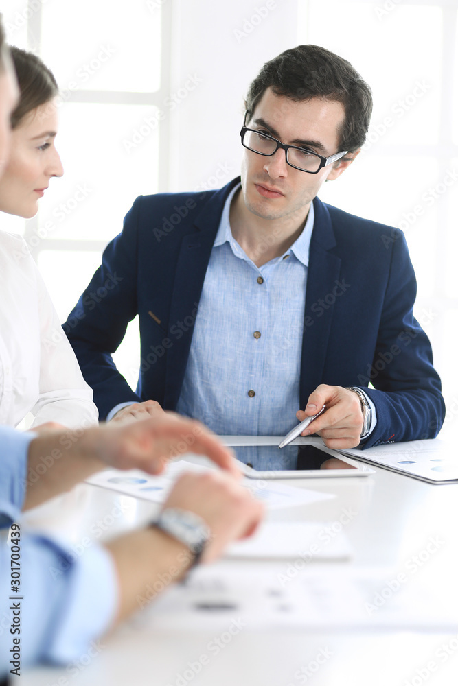 Group of business people discussing questions at meeting in modern office. Headshot of businessman at negotiation. Teamwork, partnership and business concept Group of business people discussing questions at meeting in modern office. Headshot of businessman at negotiation. Teamwork, partnership and business concept