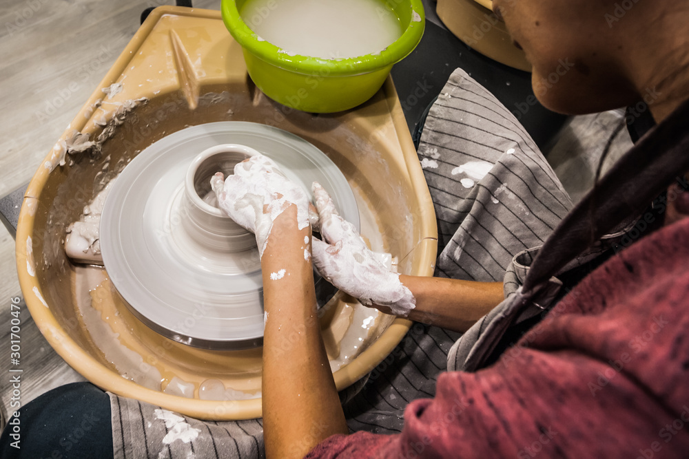 Female hands of a potter. Potter making ceramic pot on the pottery wheel. Concept for woman in freelance, business, hobby - obrazy, fototapety, plakaty 