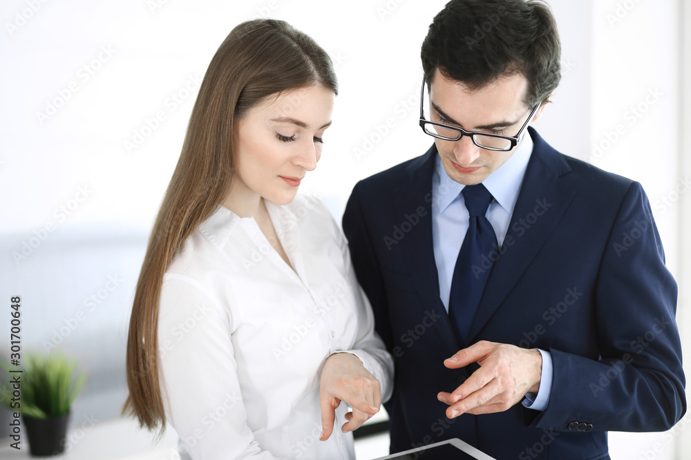 Businessmen and woman using tablet computer in modern office. Colleagues or company managers at workplace. Partners discussing contract. Business concept Businessmen and woman using tablet computer in modern office. Colleagues or company managers at workplace. Partners discussing contract. Business concept