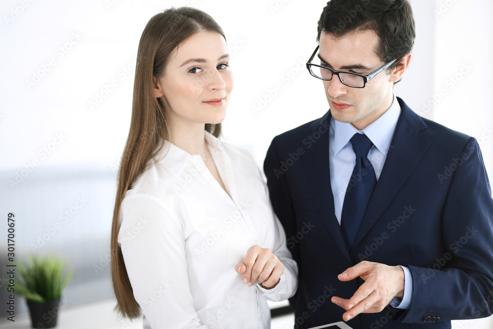 Businessmen and woman using tablet computer in modern office. Colleagues or company managers at workplace. Partners discussing contract. Business concept Businessmen and woman using tablet computer in modern office. Colleagues or company managers at workplace. Partners discussing contract. Business concept