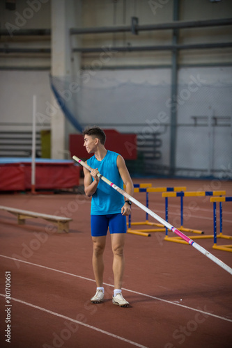 Pole vaulting - a young guy is standing with a pole in hand