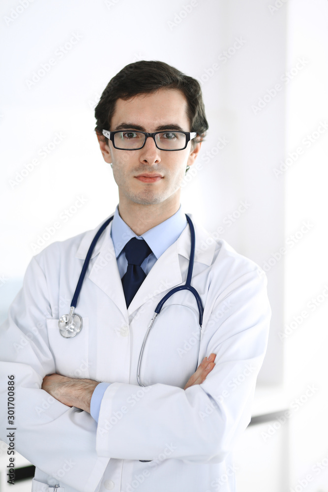 Doctor man standing straight with arms crossed. Perfect medical service in clinic. Happy future in medicine and healthcare Doctor man standing straight with arms crossed. Perfect medical service in clinic. Happy future in medicine and healthcare