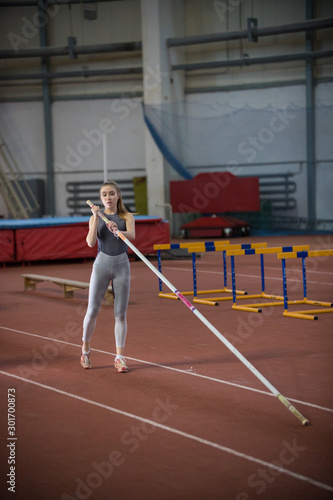 Obraz na plátně Pole vaulting - young woman is holding a long pole in her hands