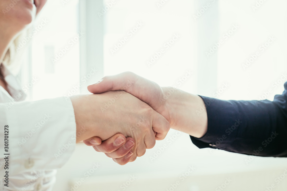 Shaking hands, concept for teamwork: Close up of man and woman shaking hands in the office Shaking hands, concept for teamwork: Close up of man and woman shaking hands in the office