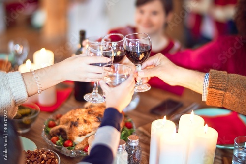 Beautiful family smiling happy and confident. Eating roasted turkey toasting with cup of wine celebrating christmas at home