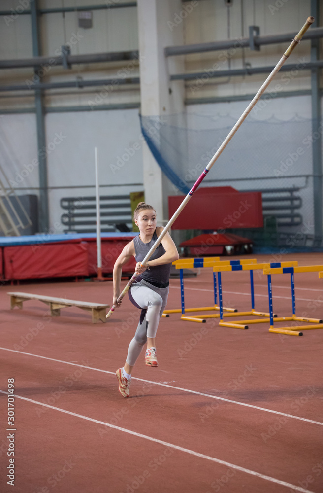 Pole vaulting - young woman is scattering with pole in hands
