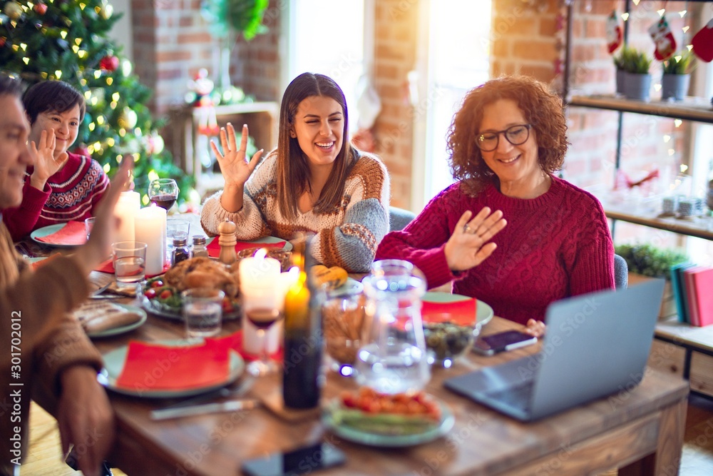 Beautiful family smiling happy and confident. Eating roasted turkey make videocall using laptop celebrating christmas at home Beautiful family smiling happy and confident. Eating roasted turkey make videocall using laptop celebrating christmas at home