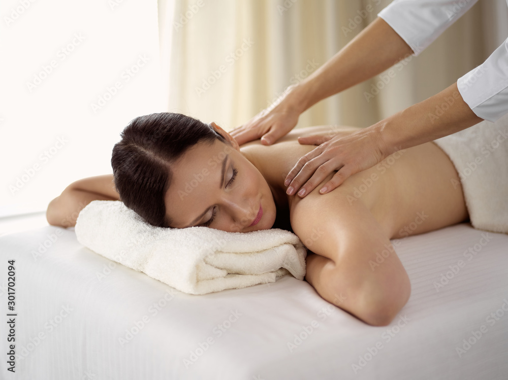 Pretty brunette woman enjoying procedure of back massage in spa salon. Beauty concept Pretty brunette woman enjoying procedure of back massage in spa salon. Beauty concept