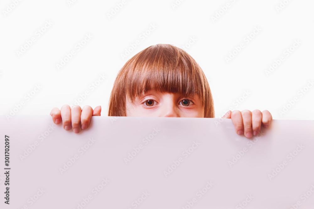 Cute little child girl looking behind white empty banner.