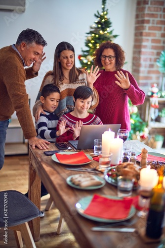 Beautiful family smiling happy and confident. Eating roasted turkey make videocall using laptop celebrating christmas at home