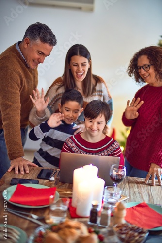 Beautiful family smiling happy and confident. Eating roasted turkey make videocall using laptop celebrating christmas at home