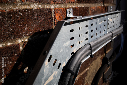 Mild steel heavy duty pre galvanised cable tray mounted on external brick wall to support electrical wiring 