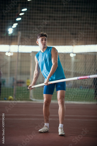 Pole vaulting - young guy in a blue suit is standing with a pole in hands © KONSTANTIN SHISHKIN