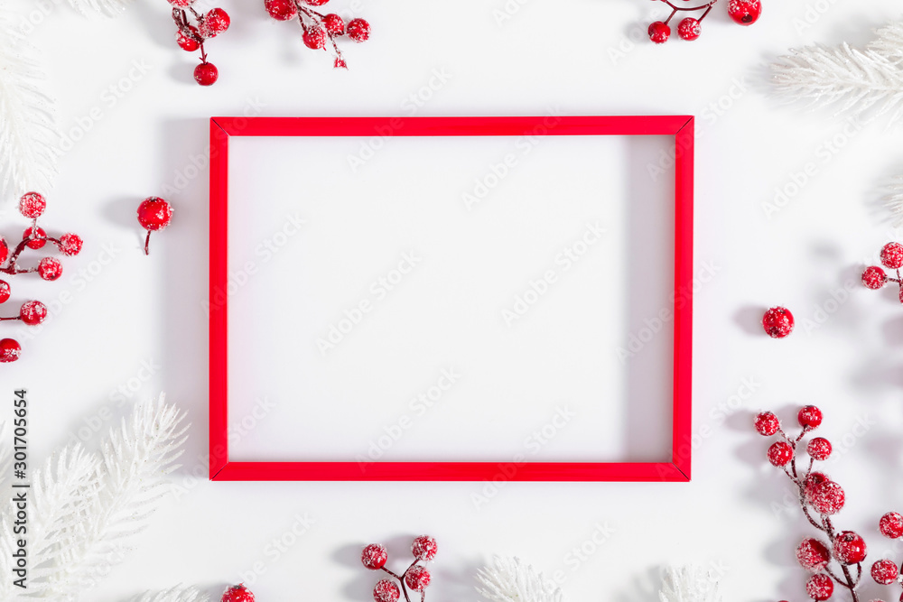 Christmas holiday composition. Red photo frame, white fir tree branches and red berry on white background. Christmas, New Year, winter concept. Flat lay, top view, copy space