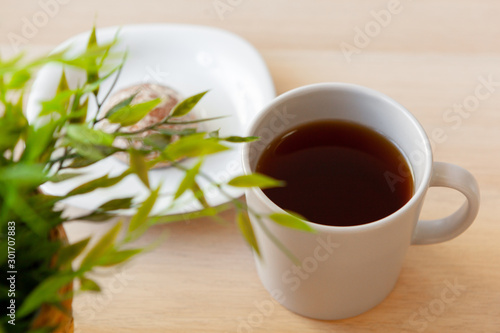 Cup of hot black tea close up on wooden table