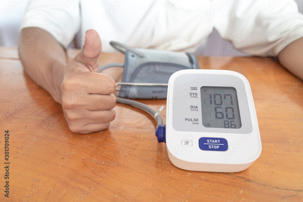 Asian male is checking blood pressure and heart rate with digital pressure gauge Asian male is checking blood pressure and heart rate with digital pressure gauge