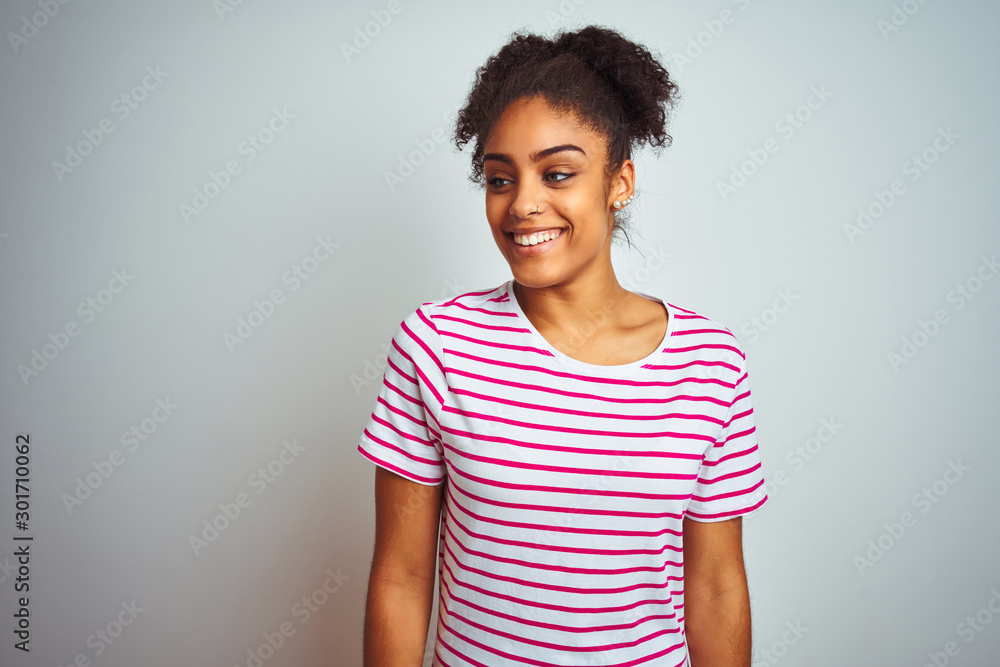 African american woman wearing casual pink striped t-shirt over isolated white background looking away to side with smile on face, natural expression. Laughing confident. African american woman wearing casual pink striped t-shirt over isolated white background looking away to side with smile on face, natural expression. Laughing confident.