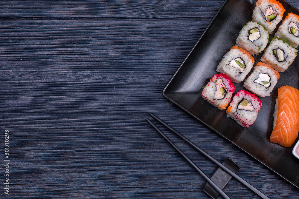 Japanese sushi and rolls with soy sauce and ginger. On a black rustic background Japanese sushi and rolls with soy sauce and ginger. On a black rustic background
