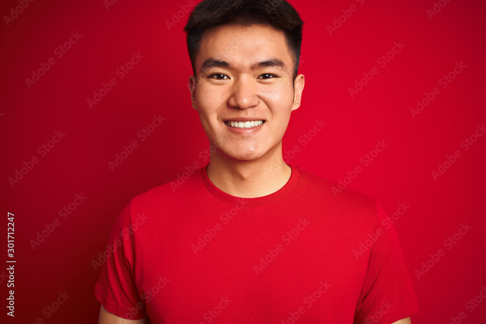 Young asian chinese man wearing t-shirt standing over isolated red background with a happy face standing and smiling with a confident smile showing teeth Young asian chinese man wearing t-shirt standing over isolated red background with a happy face standing and smiling with a confident smile showing teeth