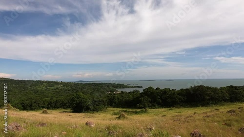 A time-lapse of clouds moving over Lake Victoria in East Africa on a hot day with a forest and Savannah grass in the foreground. photo