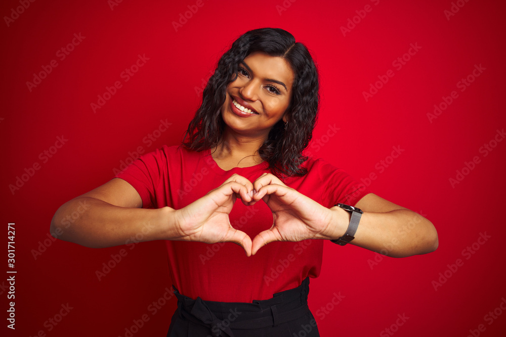 Fototapeta premium Beautiful transsexual transgender woman wearing t-shirt over isolated red background smiling in love doing heart symbol shape with hands. Romantic concept.