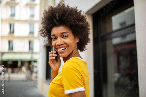 Close up of beautiful young african american woman talking with cellphone in city