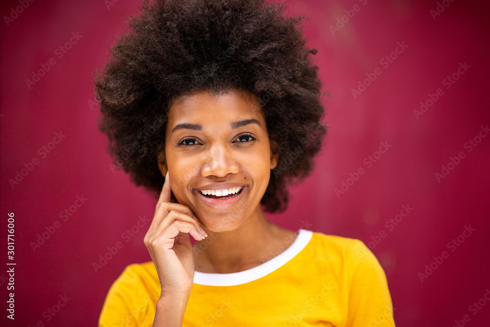 Close up front of beautiful young black woman with afro hairstyle smiling against red background Close up front of beautiful young black woman with afro hairstyle smiling against red background