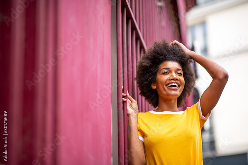 happy african American woman laughing outside with hand in hair