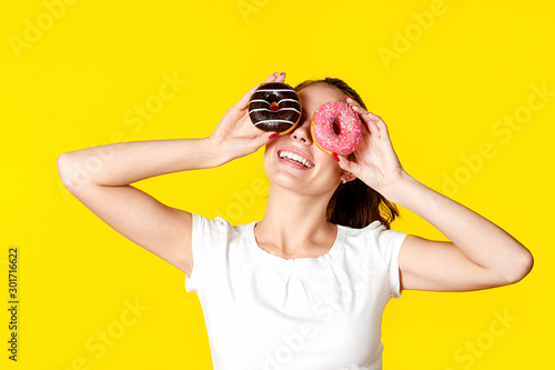 Wallpaper Mural Beautiful girl makes glasses from donuts in the glaze. On a bright yellow background. Torontodigital.ca